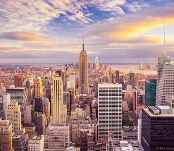 A sweeping view of Manhattan skyscrapers at sunset, with the Empire State Building near center.
